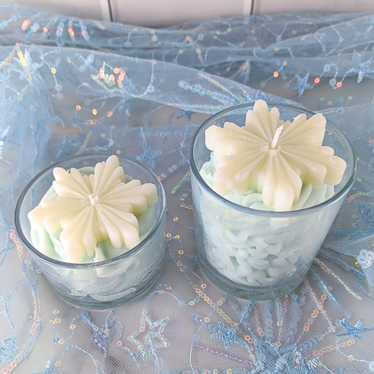 Two small glass decorative candles on a decorative cloth.