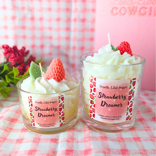 Two strawberry-themed candles on a checkered tablecloth with a blurred background.