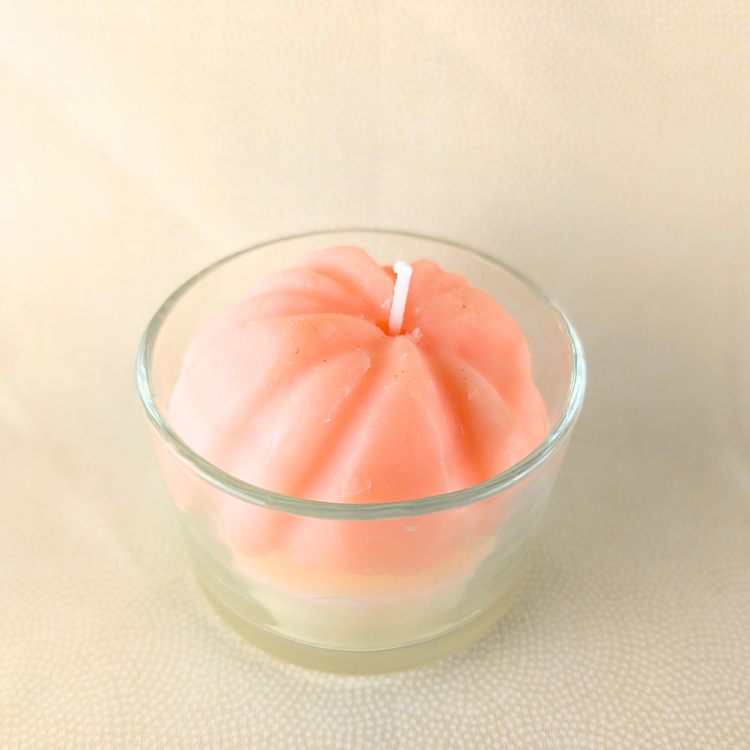 Pink candle in a glass holder on a beige background