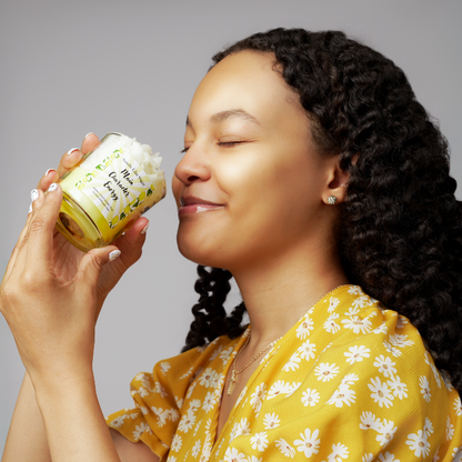 Woman holding a jar of cream with a gray background.