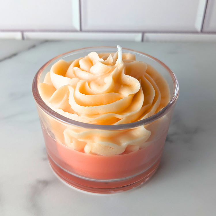 Candle in a glass holder with a wavy design on a white surface