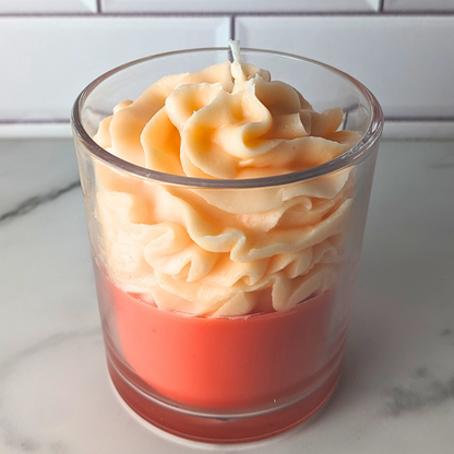 Candle in a glass container with a wavy design on a white surface.