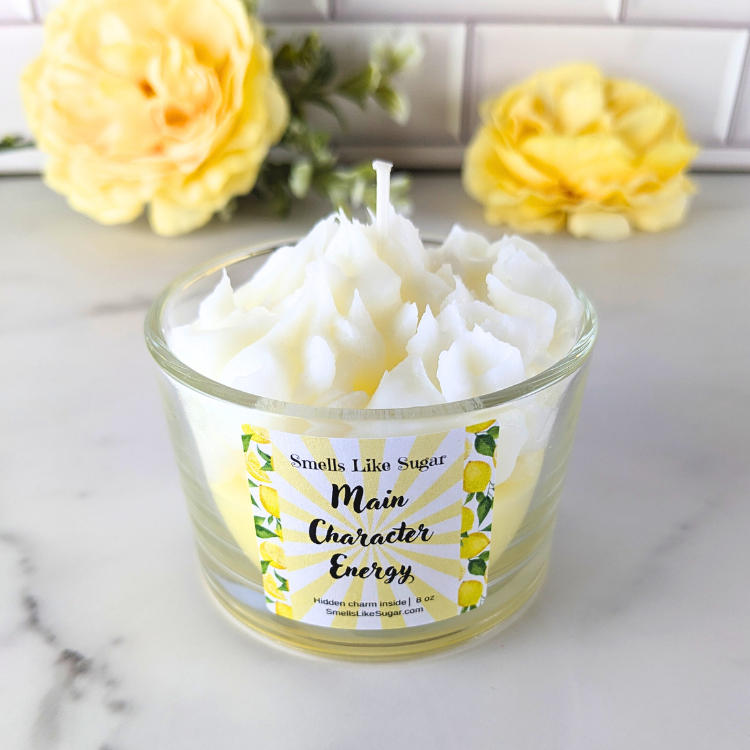 Candle in a glass jar with a label on a marble surface with yellow flowers in the background.