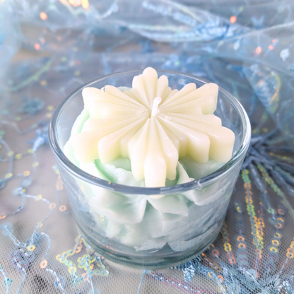 Decorative candle in a glass container on a festive background with tinsel.