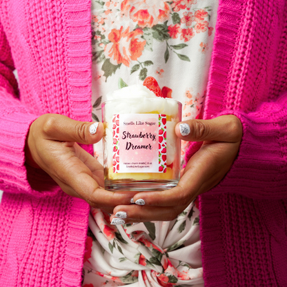 Person holding a 'Strawberry Dreamer' candle with a floral background.