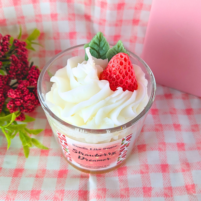 Wax whipped cream and a wax strawberry on a checkered tablecloth.