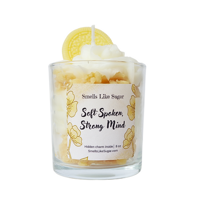 Candle with a label reading 'Smells Like Sugar, Soft Spoken, Strong Mind' on a white background