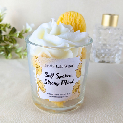 Candle with a label reading 'Smells Like Sugar Soft Spoken, Strong Mind' on a light background.